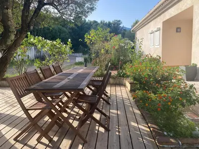 a wooden table and chairs on a wooden deck at Villa ALETTI MJ piscine privée Porto Vecchio in Porto-Vecchio