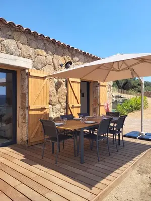 a wooden deck with a table and an umbrella at Alivu bergerie Sotta hyper cosy in Sotta