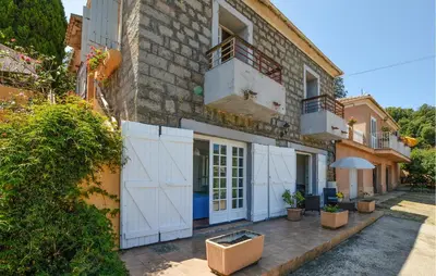 a building with white doors and a fence at Appartement Calanches Piana in Piana