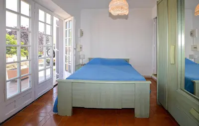 a bedroom with a bed with blue sheets and windows at Appartement Calanches Piana in Piana