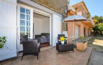 a patio with chairs and an umbrella and a couch at Appartement Calanches Piana in Piana