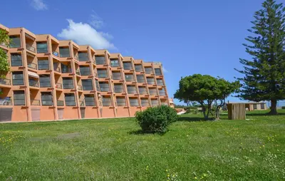 a large brick building in a field of grass at Studio Piscine Et Plage in Furiani