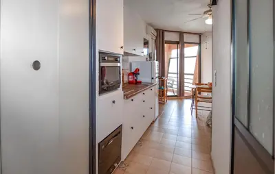 a kitchen with white cabinets and a refrigerator at Studio Piscine Et Plage in Furiani