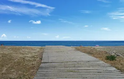 a wooden path leading to a beach with the ocean at Studio Piscine Et Plage in Furiani