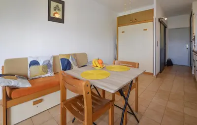 a kitchen and dining room with a table and a couch at Studio Piscine Et Plage in Furiani