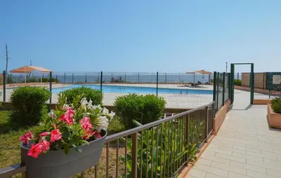 a balcony with a fence with flowers and a swimming pool at Studio Piscine Et Plage in Furiani