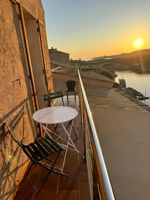 a table and chairs on a balcony with the sunset at Tana Torricella in Bonifacio