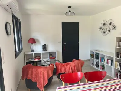 a living room with two red chairs and a black door at Maison INDEPENDANTE entre mer et montagne in Prunelli-di-Fiumorbo