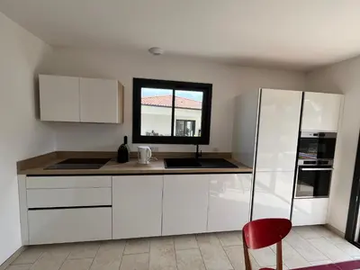 a kitchen with white cabinets and a red chair at Maison INDEPENDANTE entre mer et montagne in Prunelli-di-Fiumorbo