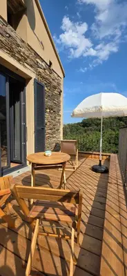 a wooden deck with a table and an umbrella at La Casuccia in Venzolasca
