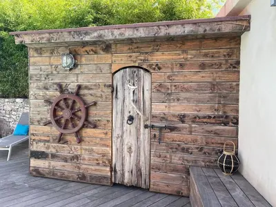 a wooden shed with a wheel on a deck at Villa les pieds dans l'eau in Bonifacio