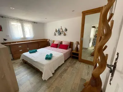 a bedroom with a bed with red pillows and a mirror at Villa les pieds dans l'eau in Bonifacio