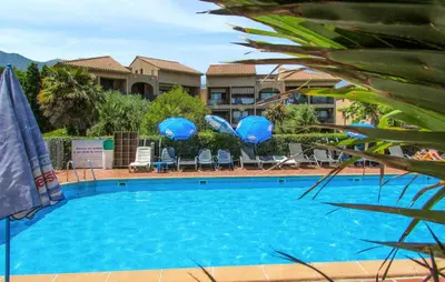 a large blue swimming pool with chairs and umbrellas at Gorgeous Apartment In Moriani Plage in Moriani Plage