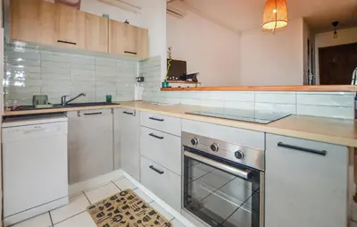 a kitchen with white cabinets and a sink and a dishwasher at Gorgeous Apartment In Moriani Plage in Moriani Plage