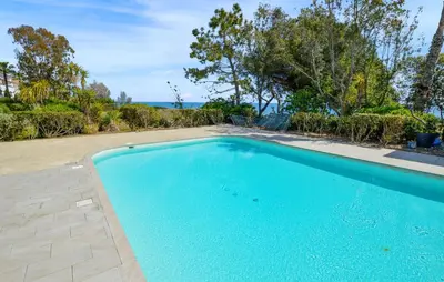 a blue swimming pool with the ocean in the background at Gorgeous Apartment In Moriani Plage in Moriani Plage