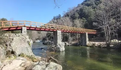 a red bridge over a river with a mountain at U San Petru -Locations de chambres in Bains de Guitera