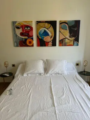 a bedroom with three paintings above a white bed at U San Petru -Locations de chambres in Bains de Guitera