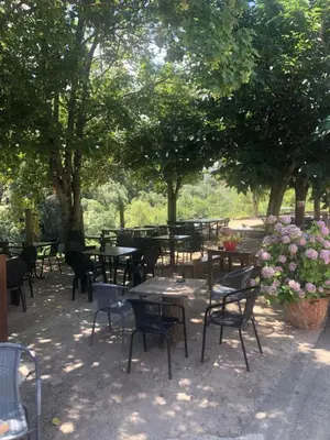 a group of tables and chairs under trees with flowers at U San Petru -Locations de chambres in Bains de Guitera