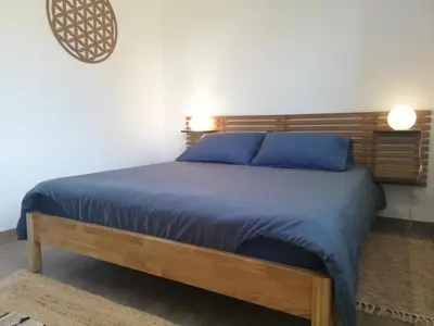 a bedroom with a bed with a wooden headboard at Agapanthe location in San-Nicolao