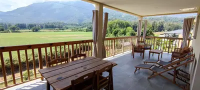 a porch with a wooden table and chairs and a view at Agapanthe location in San-Nicolao
