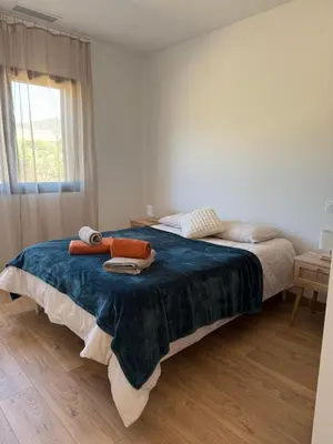 a bedroom with a bed with a blue blanket and a window at Chez Claudine & Adrien in Figari