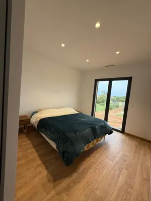 a bedroom with a bed and a large window at Chez Claudine & Adrien in Figari