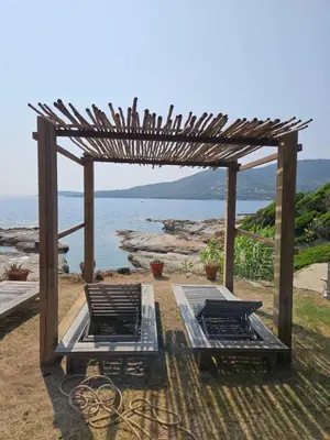 a pergola with two beds in front of the ocean at Bella Stella in Coggia
