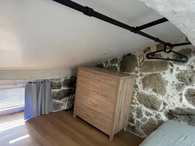 a bedroom with a stone wall and a dresser at Casa Tassinca in Tasso