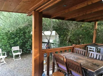 a wooden pergola with a table and chairs on a patio at Chalet cosy in Pianottoli-Caldarello