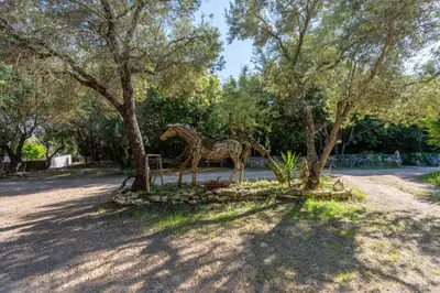 a statue of a giraffe standing next to a tree at Le Refuge du Maquis in Bonifacio