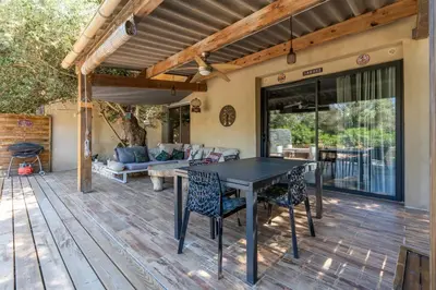 a patio with a table and chairs on a deck at Le Refuge du Maquis in Bonifacio