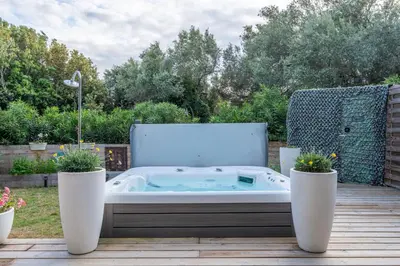 a hot tub on a deck with two potted plants at Le Refuge du Maquis in Bonifacio