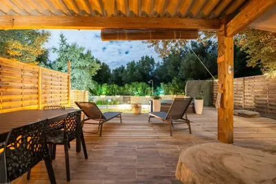 a patio with a table and chairs on a wooden deck at Le Refuge du Maquis in Bonifacio