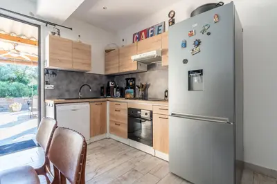 a kitchen with a white refrigerator and wooden cabinets at Le Refuge du Maquis in Bonifacio