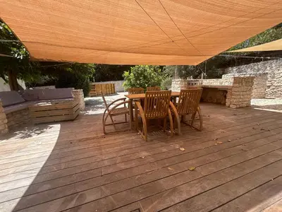 a wooden deck with a table and chairs under an umbrella at Vacances Bonifacio Bergerie in Bonifacio
