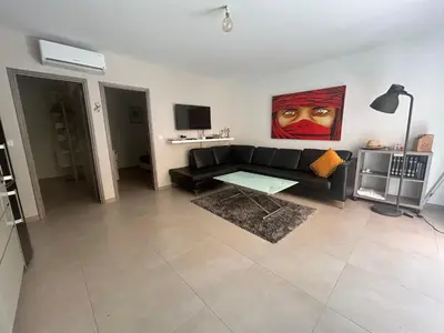 a living room with a black couch and a painting at Vacances Bonifacio Bergerie in Bonifacio