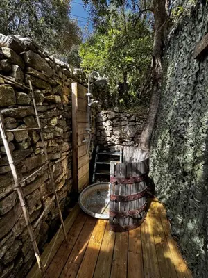 a bath tub sitting on a wooden deck with a stone wall at La Villa Maquis in Bonifacio
