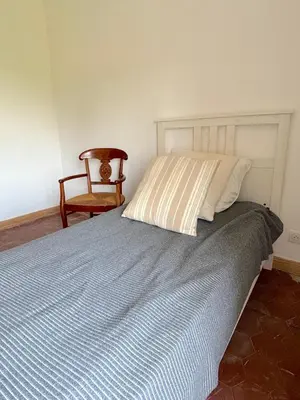 a bedroom with a bed with a chair and a pillow at L'appartement Montecristo in Aléria