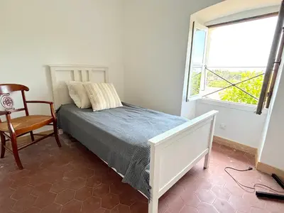 a bedroom with a bed and a chair and a window at L'appartement Montecristo in Aléria