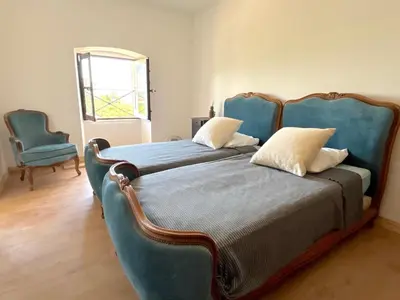 a bedroom with two beds with blue chairs and a window at L'appartement Montecristo in Aléria