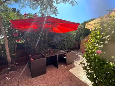 a red umbrella over a table in a garden at Le Maquis in Alata