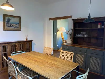 a dining room with a wooden table and chairs at Au coeur de Sartène appartement de charme dans un écrin de verdure in Sartène