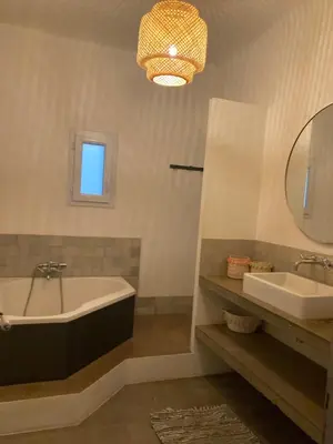 a bathroom with a tub and a sink and a mirror at Au coeur de Sartène appartement de charme dans un écrin de verdure in Sartène