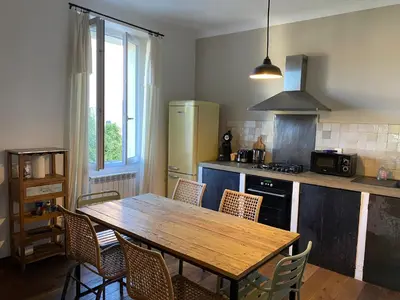 a kitchen with a wooden table and chairs in it at Au coeur de Sartène appartement de charme dans un écrin de verdure in Sartène