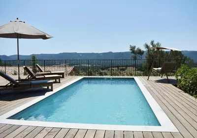 a pool on a wooden deck with chairs and an umbrella at Bergerie avec piscine chauffée Sotta in Sotta