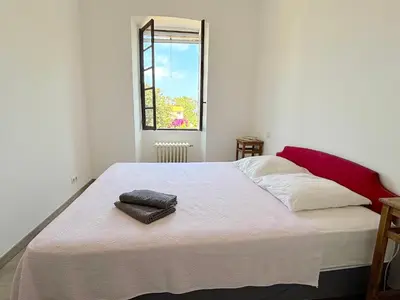 a bedroom with a large white bed with a window at L'appartement Pianosa in Aléria