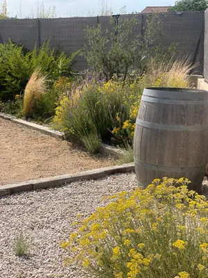 a garden with a wooden barrel in the middle of flowers at La Villa Geneviève, Maison 6 personnes avec piscine in Calenzana