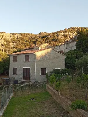 a gray house with a hill in the background at Casa di Purgu in Sotta