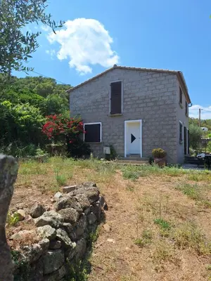 a stone house with a stone wall in front of it at Casa di Purgu in Sotta