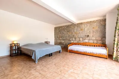 a bedroom with a bed and a stone wall at Parad'Isula - Avec piscine à Porticcio in Grosseto-Prugna